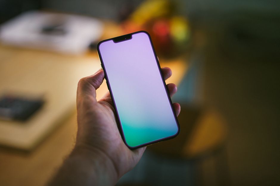A close-up of a hand holding a smartphone inside a stylish home, representing managing guest communication through a platform app.