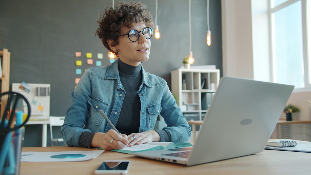 A focused property manager in a modern office setting, intently reviewing financial documents and a laptop, strategizing for better ROI.