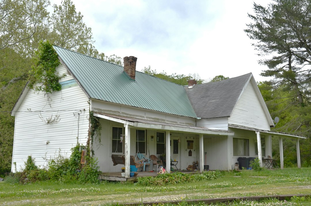 A close-up, high-quality photograph of weathered house siding with cracked and peeling paint, representing how neglecting home maintenance erodes property value.